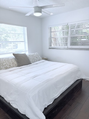 Ein Schlafzimmer mit einem Bett, einem Deckenventilator und einem Fenster mit Jalousien.