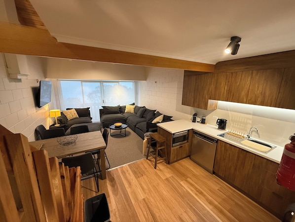 A compact living space with a kitchenette, a dining area, and a seating area with a sofa and chairs. - Razorback 4 - Mt Hotham (Hotham Heights)
