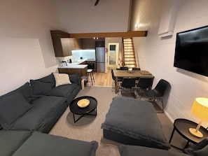 A compact living space with a sofa, a dining table, and a TV mounted on the wall. - Razorback 4 - Mt Hotham (Hotham Heights)