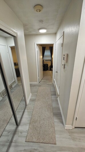 Un couloir avec un tapis, des murs blancs et des portes donnant sur différentes pièces.
