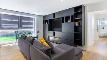 A modern living room with a grey sofa, a flat-screen TV, and built-in shelving.