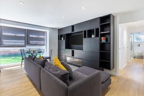 A modern living room with a grey sofa, a flat-screen TV, and built-in shelving. - Modern 2-Bed | 5 Mins to Ealing Broadway Station (London)