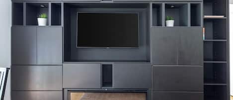 A modern living room with a flat-screen TV, built-in shelving, and a fireplace.