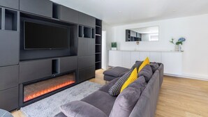A modern living room with a flat-screen TV, built-in entertainment unit, and a fireplace.