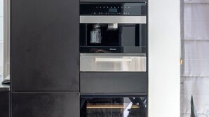 A modern kitchen with built-in appliances, a dining table, and a chair.