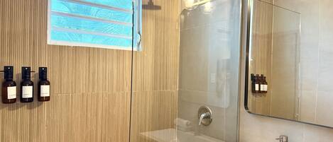 Un baño moderno con cabina de ducha de vidrio, un espejo grande y un lavabo.