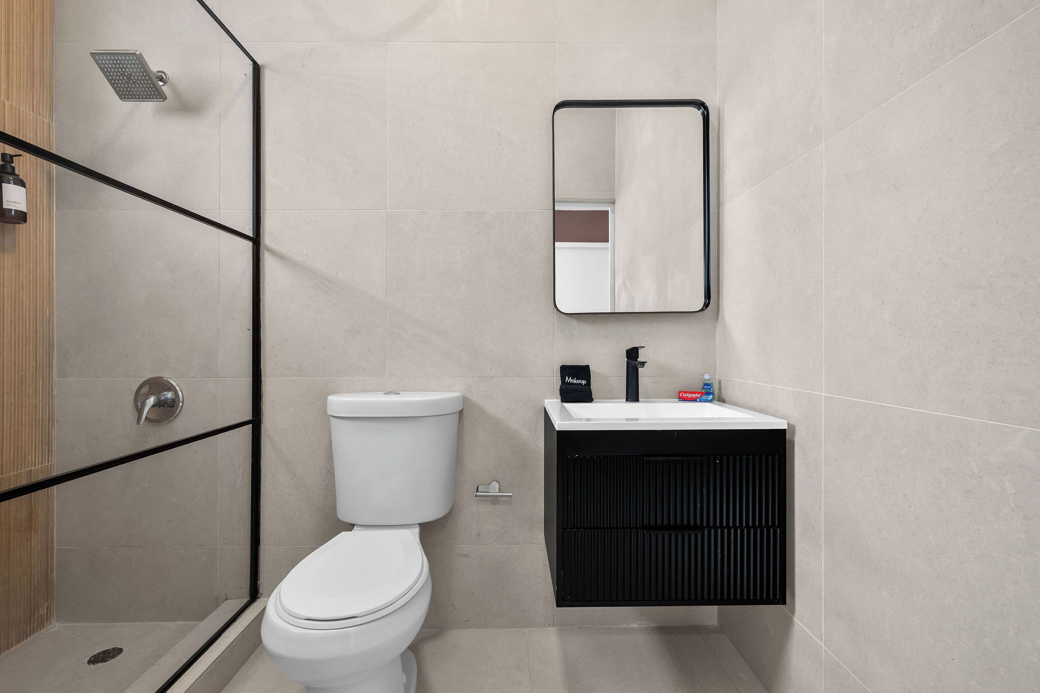 A modern bathroom with a toilet, shower, and sink.