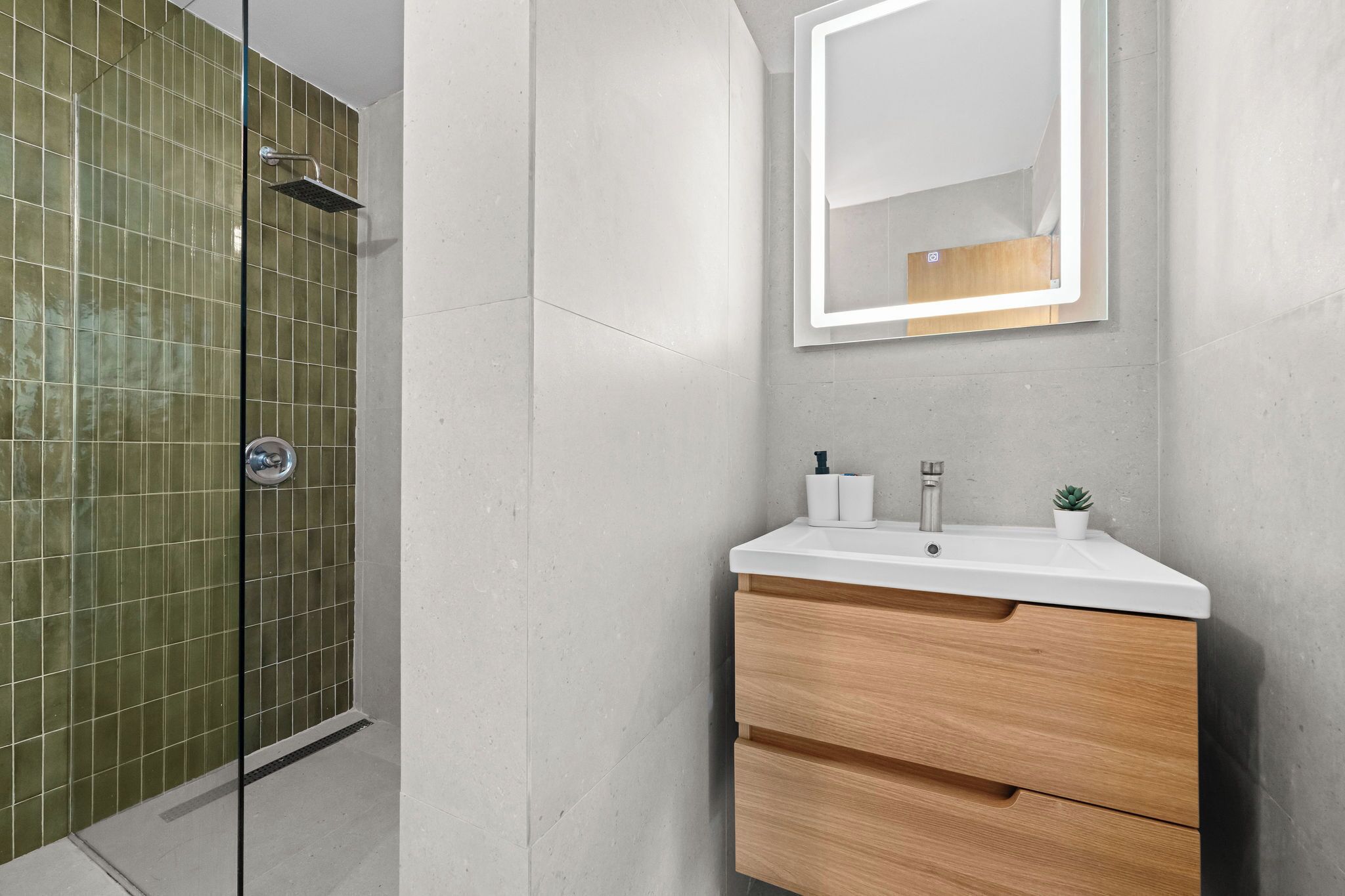 A bathroom with a shower, a sink with a mirror, and a wooden vanity.