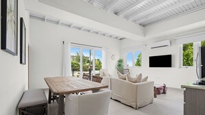 Ein geräumiger Wohnbereich mit einem Holztisch und Stühlen, einem Sofa und einem an der Wand befestigten Fernseher.