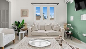 Ein Wohnzimmer mit einer Couch, einem Couchtisch, einer Pflanze und einem Fenster mit Blick.
