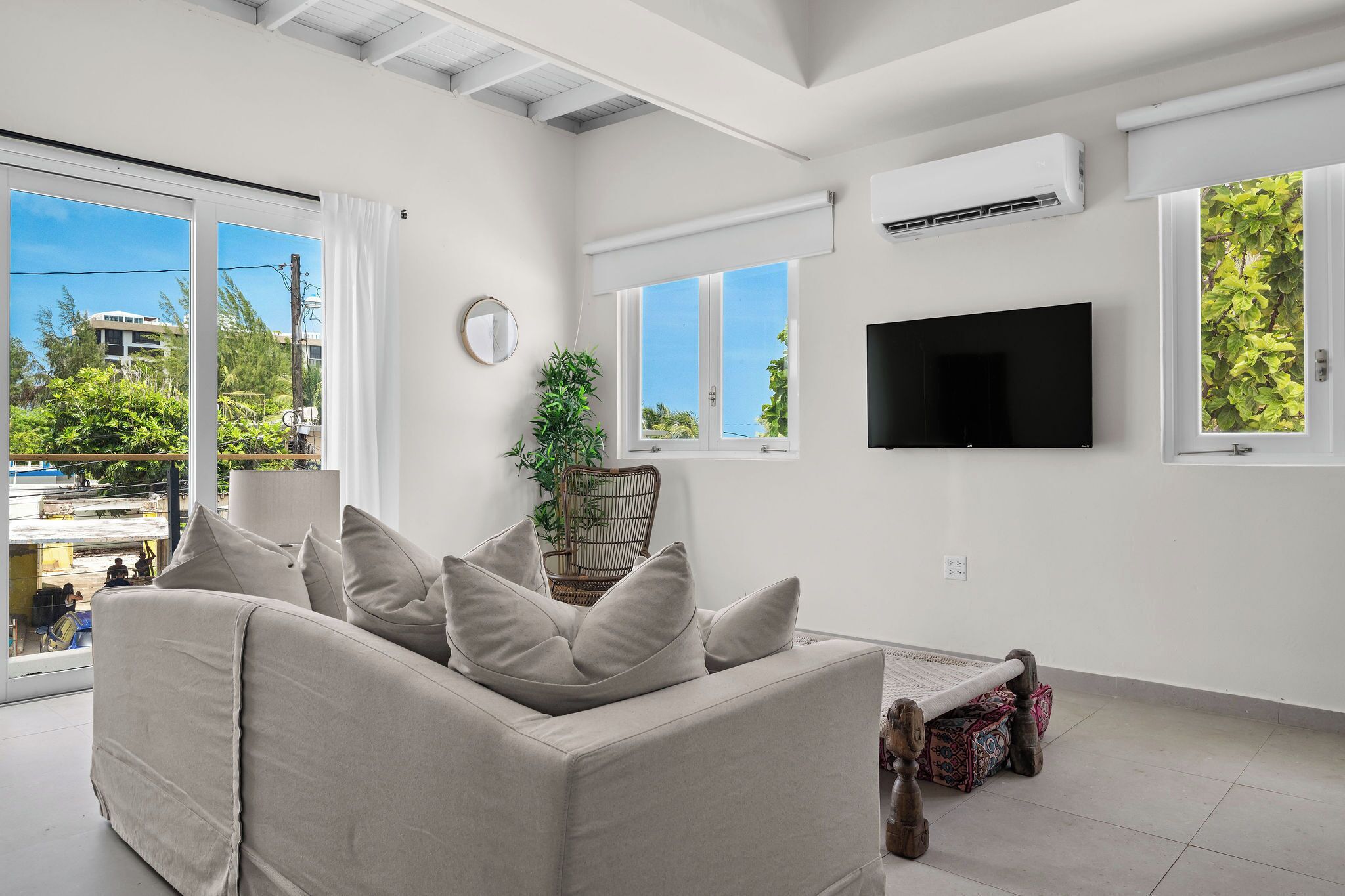 A modern living room with a sofa, a TV, and a large window.