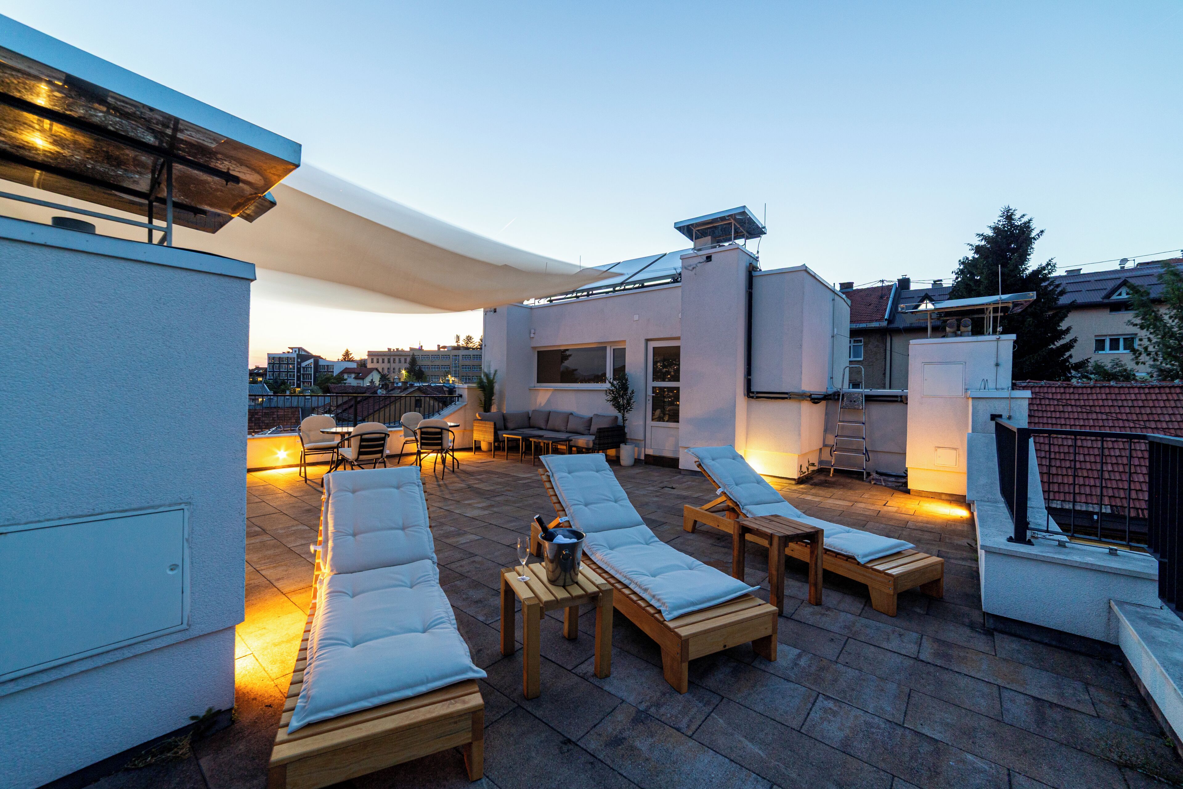A rooftop terrace with outdoor seating, a canopy, and a view of the cityscape.