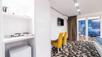 A hotel room with a dining area, a bed, a TV, and a city view.