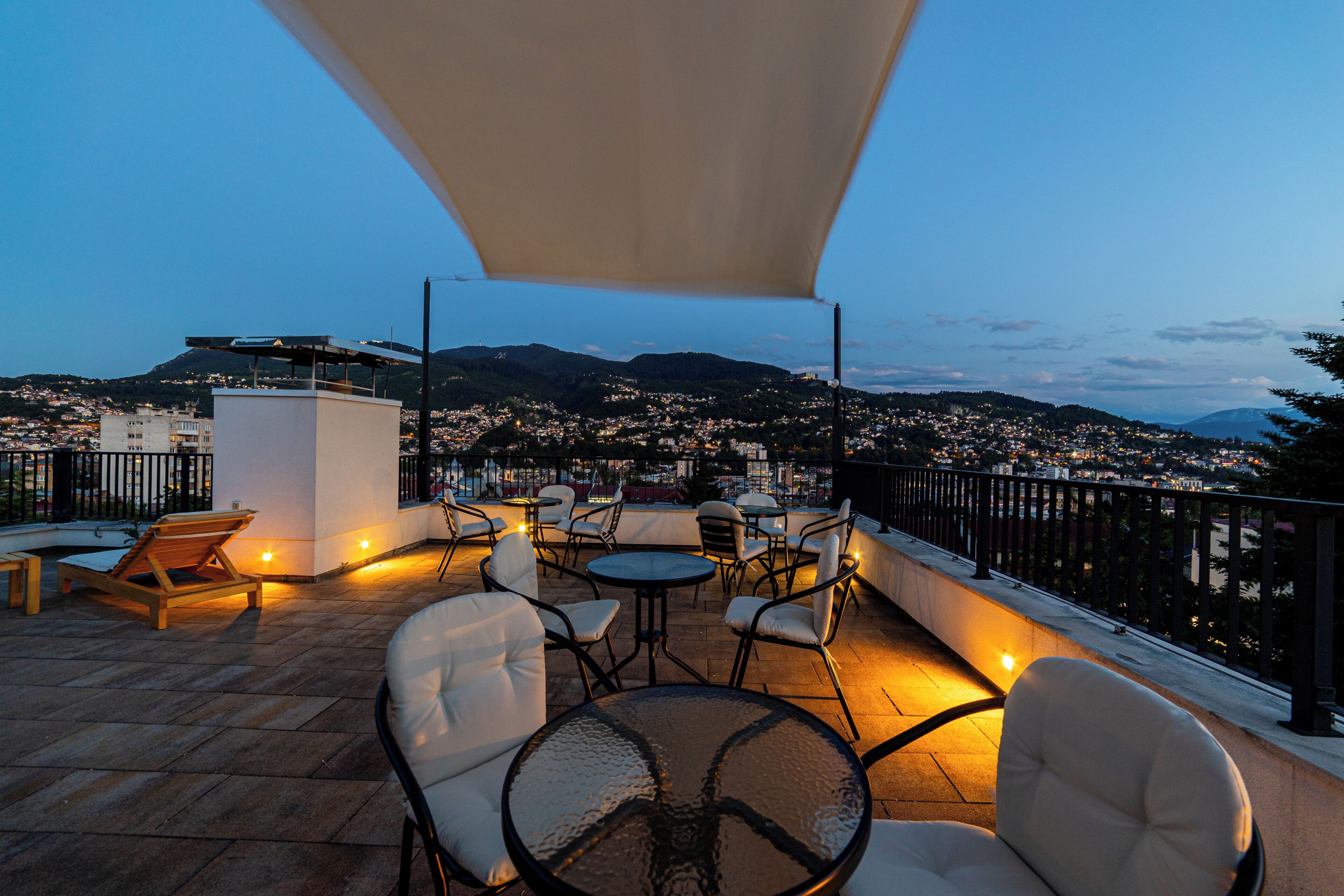 Eine Terrasse mit Sitzgelegenheiten, Blick auf eine Stadtlandschaft und ein Berg im Hintergrund.