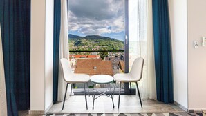 A balcony with two chairs and a small table, overlooking a cityscape with mountains. - Luxury Aparthotel MejtasHills - Old Town (Sarajevo)
