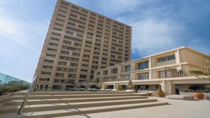 Un hotel de varios pisos con un patio central, mobiliario exterior y zona de piscina.