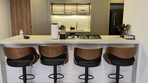 Una cocina moderna con una isla central, taburetes de bar y horno empotrado.