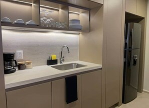Eine moderne Küche mit Spüle aus Edelstahl, einer Kaffeemaschine und einem integrierten Kühlschrank.