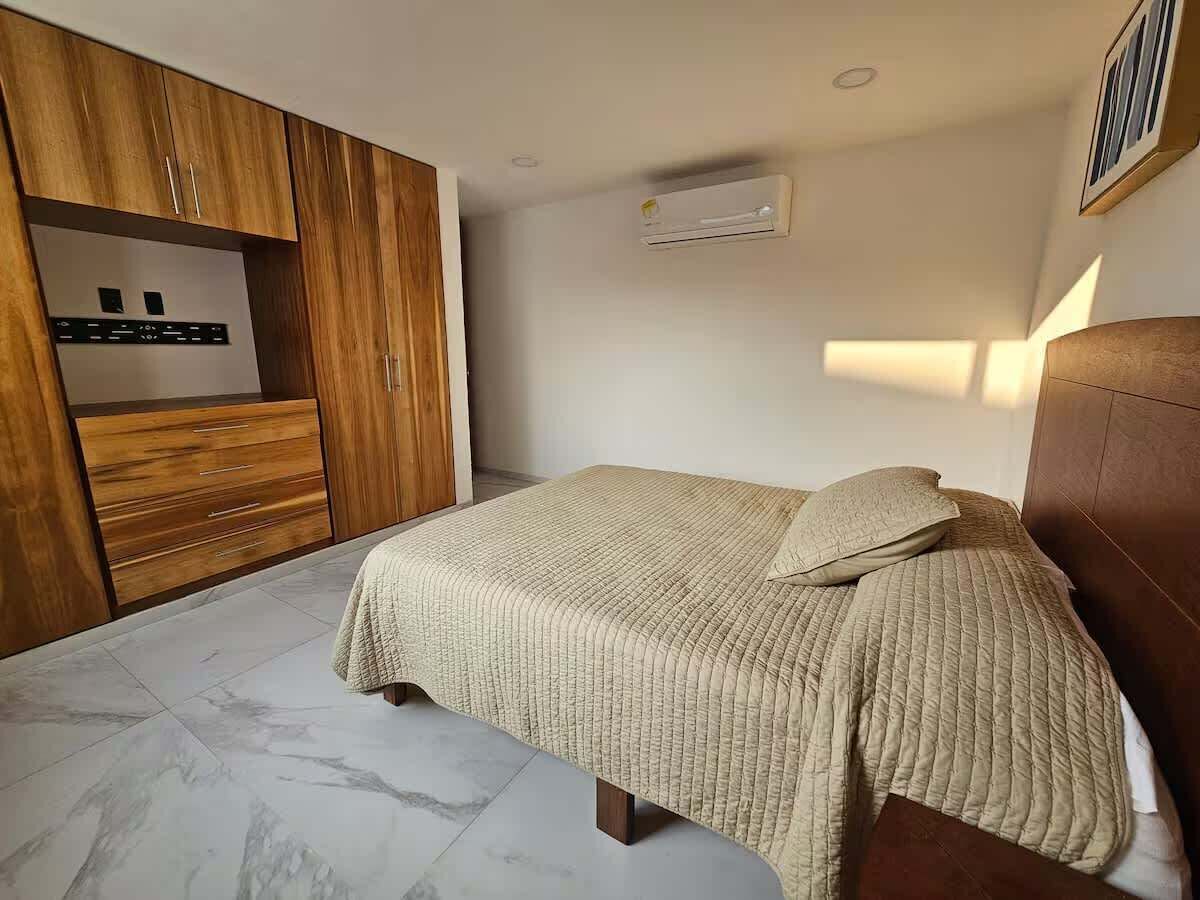 Een slaapkamer met een bed, een houten kledingkast en een airconditioning.