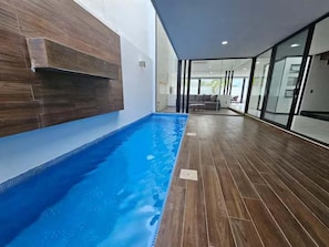 En indendørs swimmingpool med trægulv og moderne vægdesign.