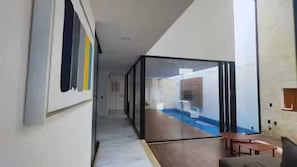 Et moderne interiør med en glasafskærmning, trægulv og udsigt til en swimmingpool.