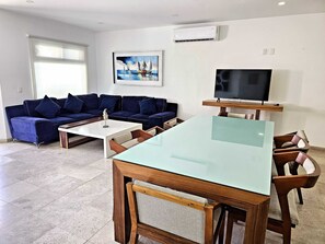 Un salon avec un canapé, une table basse, un téléviseur et un tableau accroché au mur.