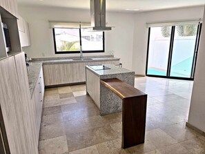 A modern kitchen with granite countertops, a built-in stove, and a large window.