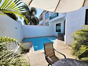 Une piscine avec une chaise et des marches menant à un bâtiment.