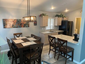 A modern kitchen with a dining area, granite countertops, wooden cabinets, and a pendant light. - Relaxing 3-Bedroom Vacation Home Relaxing Home with Pool, Golf & Tennis Sleeps 8 (Haines City)