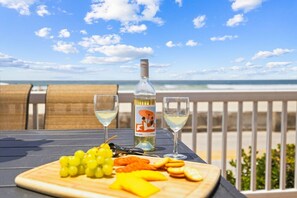 Una mesa con una botella de vino, dos copas y una variedad de frutas y aperitivos sobre una tabla de madera.