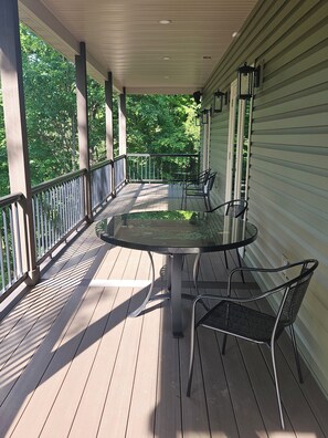 A covered outdoor patio with a round table and chairs, surrounded by a white railing. - Rural setting with easy access to 4-season activities. (Fort Hill)