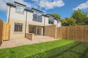 A two-story house with a patio, a wooden fence, and a grassy yard. - Apartment in Edinburgh Newington (Edinburgh)