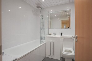 A bathroom with a glass-enclosed shower, a white sink, and a toilet. - Apartment in Edinburgh Newington (Edinburgh)