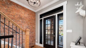 A staircase with a wooden handrail, a black door with glass panels, and a white wall with a mounted deer head. - Historic Home Near Downtown - Sleeps 14 - Arcade (Columbus)