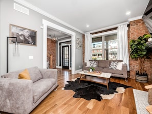 Una sala de estar moderna con un sofá gris, un sofá marrón, una mesa de centro y un tapete blanco y negro.