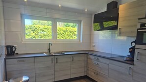 Una cocina moderna con ventana, electrodomésticos de acero inoxidable y muebles de madera clara.