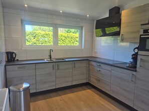Une cuisine moderne avec une fenêtre, des appareils en acier inoxydable et des meubles de cuisine en bois clair.