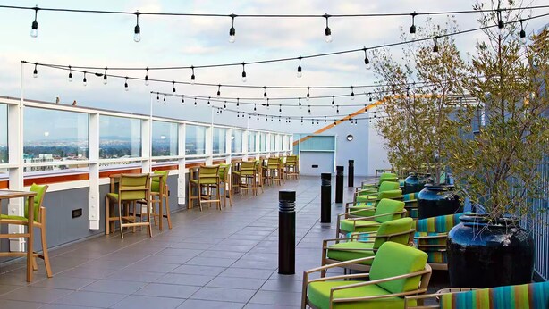 A rooftop terrace with a row of chairs and tables, a view of the city, and string lights. - Wyndham Large Luxury 2 Bedroom Suite w/Kitchen Next to Disneyland. Book by 6/29 (Anaheim)