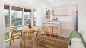 A modern kitchen with a dining area, large windows, and a view of the outside. - Sunset Drift Edithvale Steps to Beach (Edithvale)