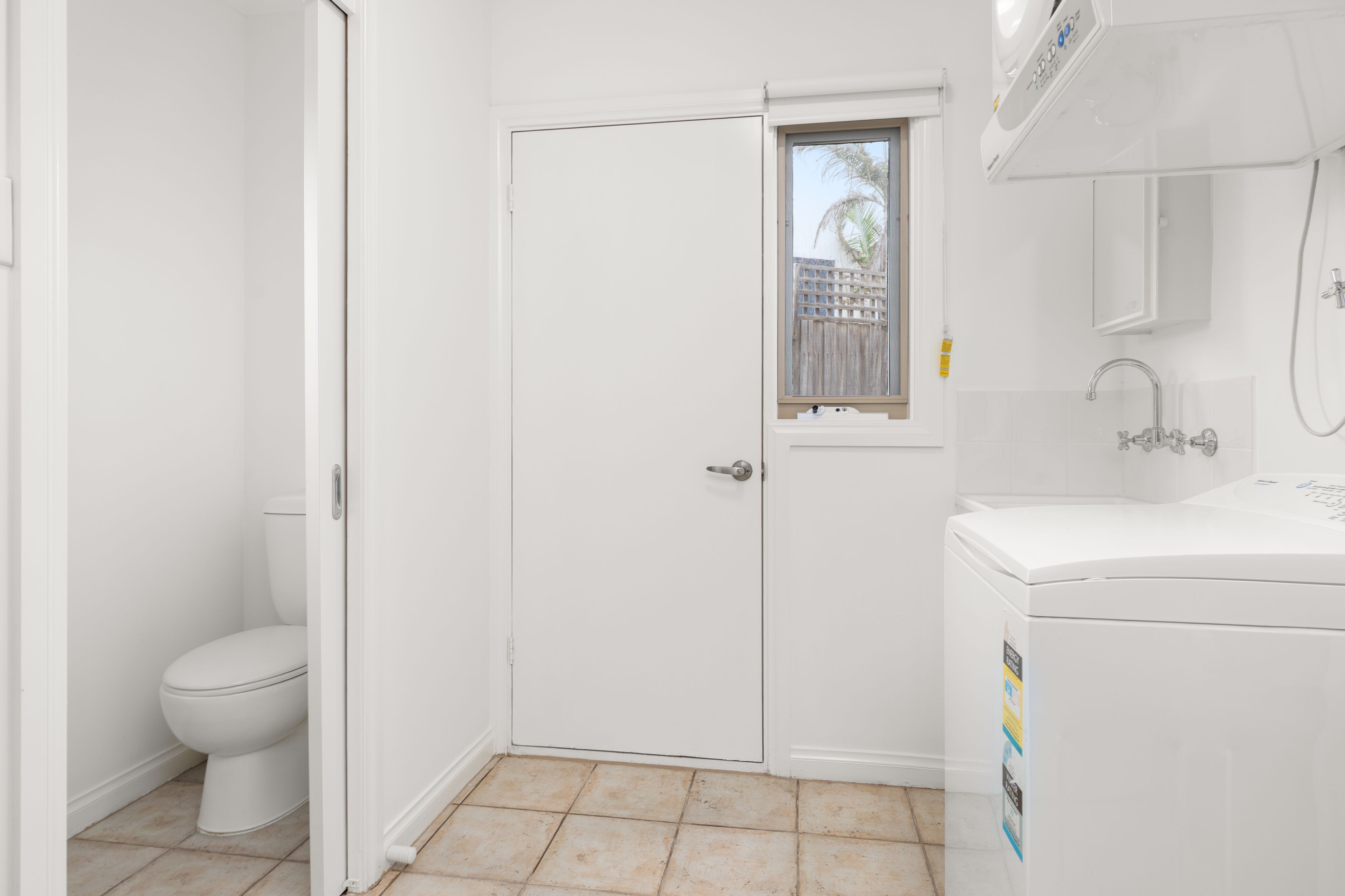 A small, white bathroom with a toilet, a window, and a sink.