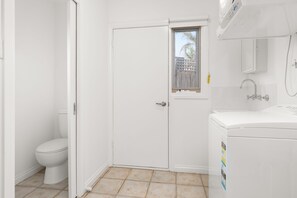 A small, white bathroom with a toilet, a window, and a sink.
