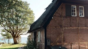 A traditional brick house with a thatched roof, a stone pathway, and a view of the water. - 4 Star Holiday Home in Faaborg (Faaborg)