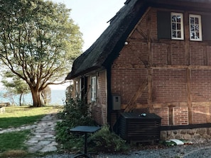 A traditional brick house with a thatched roof, a stone pathway, and a view of the water. - 4 Star Holiday Home in Faaborg (Faaborg)