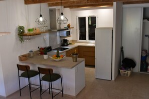 A kitchen with a central island, bar stools, a microwave, and a hanging light fixture. - A heavenly spot in gigaro, 5min from pl6 (La Croix-Valmer)