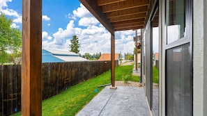 A covered outdoor area with a wooden deck, a stone pathway, and a view of a residential neighborhood.
