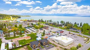 A town with a large body of water, a mix of residential and commercial buildings, and a mountainous backdrop.