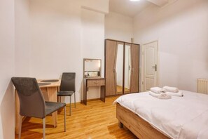 Une chambre à coucher avec un lit en bois, un bureau avec une chaise, une armoire et un miroir.