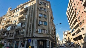 Un edificio de varios pisos con balcones, una señal de paso para peatones y vista a la calle.