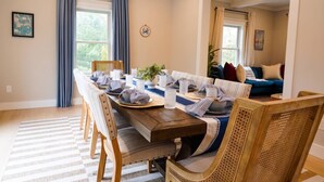 Een eetgedeelte met een houten tafel voor zes personen, omringd door rieten stoelen.