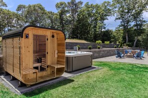 Une structure de sauna en bois, avec un banc et un bain à remous, située dans un jardin aménagé.